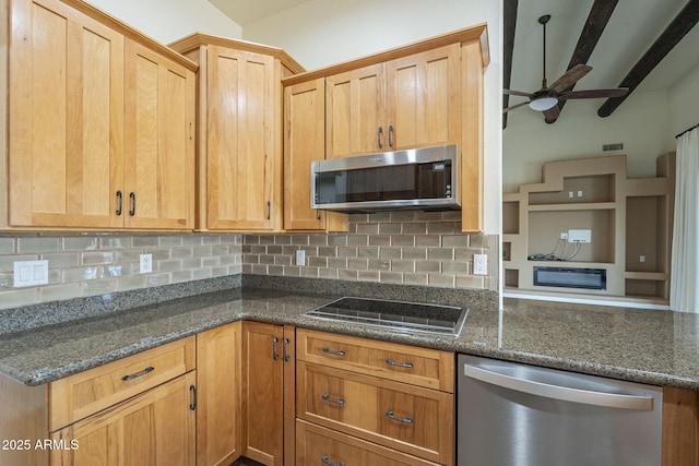 kitchen with appliances with stainless steel finishes, dark stone counters, and tasteful backsplash