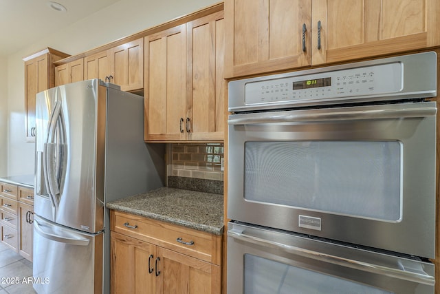 kitchen with stainless steel appliances, stone countertops, light brown cabinets, and decorative backsplash