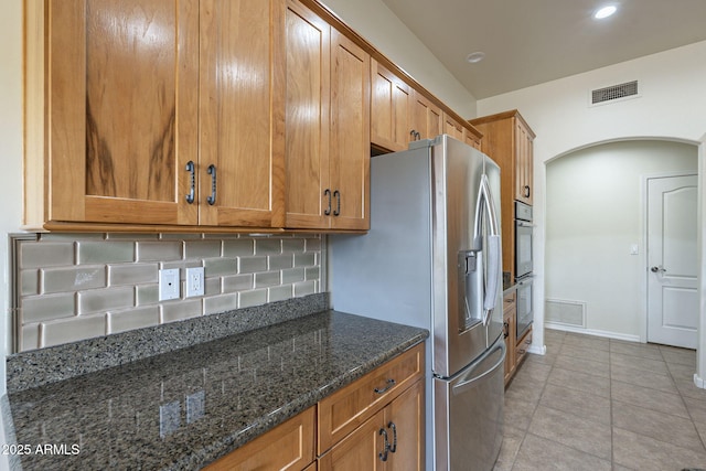 kitchen with brown cabinetry, visible vents, and stainless steel refrigerator with ice dispenser