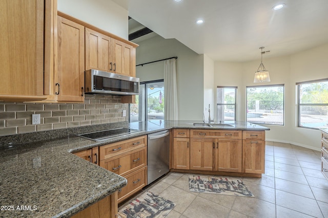 kitchen with stainless steel appliances, a peninsula, a sink, a healthy amount of sunlight, and decorative backsplash