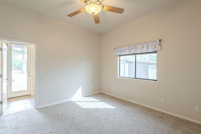 carpeted spare room with ceiling fan, baseboards, and tile patterned flooring