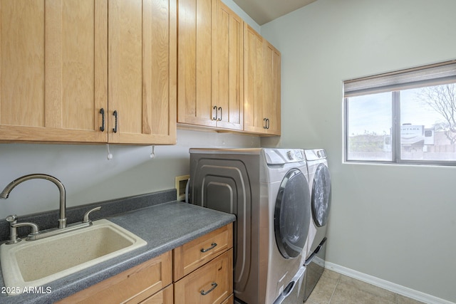 clothes washing area featuring a sink, baseboards, washer and dryer, cabinet space, and tile patterned floors
