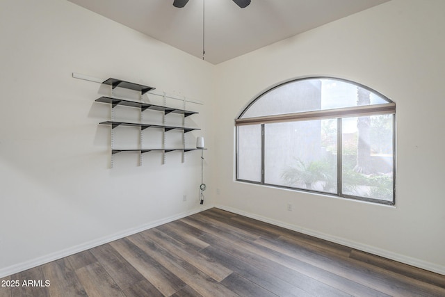 empty room with dark wood finished floors, baseboards, and ceiling fan