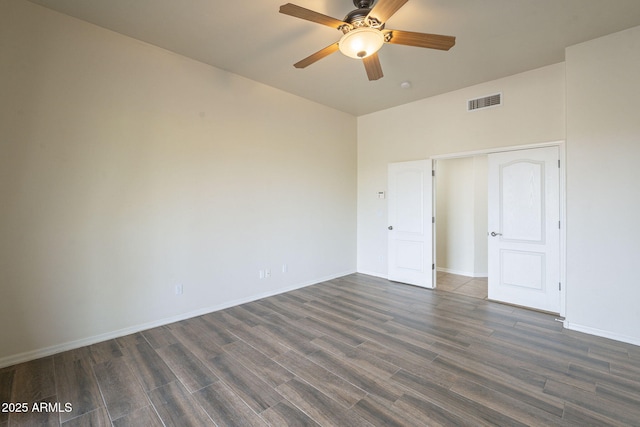 unfurnished room with ceiling fan, dark wood finished floors, visible vents, and baseboards