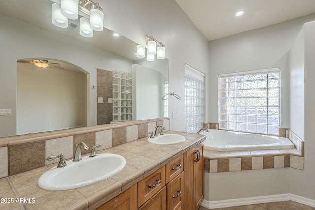 full bathroom featuring a bath, ceiling fan, double vanity, and a sink