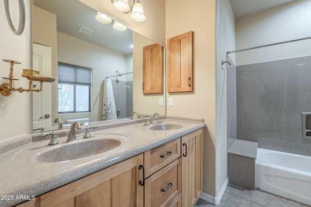 bathroom with double vanity, a sink, visible vents, and baseboards