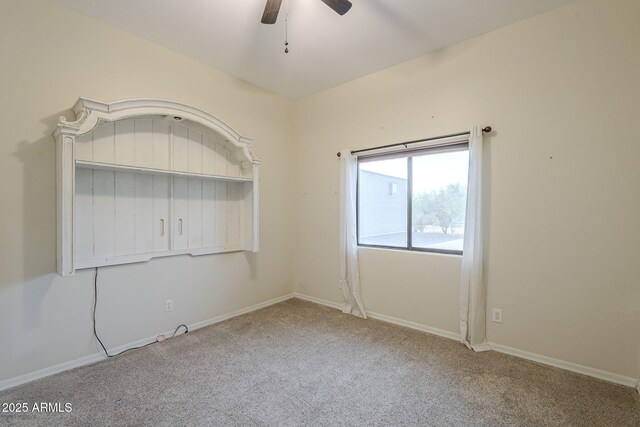 carpeted spare room with ceiling fan and baseboards