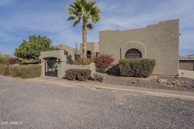 view of front of house featuring a fenced front yard, a gate, and stucco siding