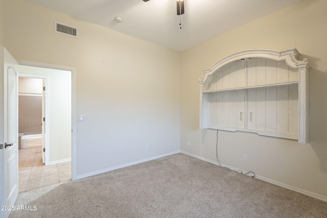 spare room featuring baseboards, carpet, visible vents, and a ceiling fan