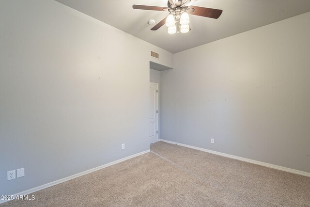 spare room featuring a ceiling fan, light colored carpet, and baseboards