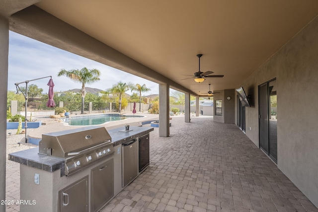 view of patio featuring a fenced in pool, a ceiling fan, area for grilling, fence, and exterior kitchen