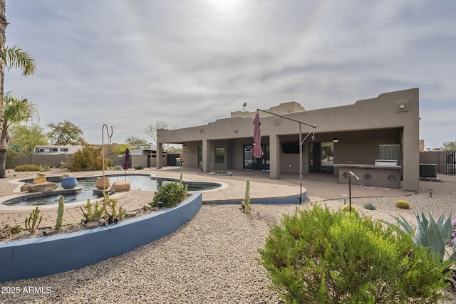 back of property featuring a patio, central AC unit, an outdoor kitchen, a fenced in pool, and stucco siding