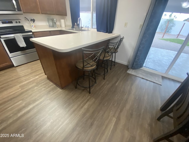 903 W Jacinto Cir, Mesa, AZ 85210 - kitchen with appliances with stainless steel finishes, light wood-style floors, a breakfast bar area, light countertops, and a peninsula