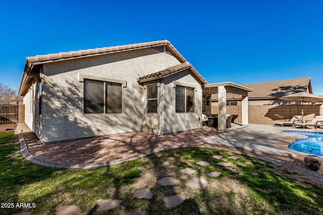 rear view of property with a fenced in pool and a patio area