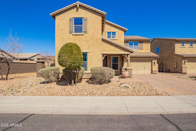 view of front of property with fence, a tiled roof, stucco siding, decorative driveway, and a garage