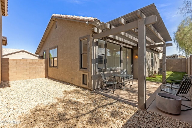 rear view of property with stucco siding, a tile roof, a pergola, fence, and a patio area