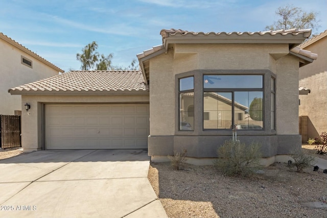 view of front of home featuring stucco siding, driveway, a tile roof, and a garage