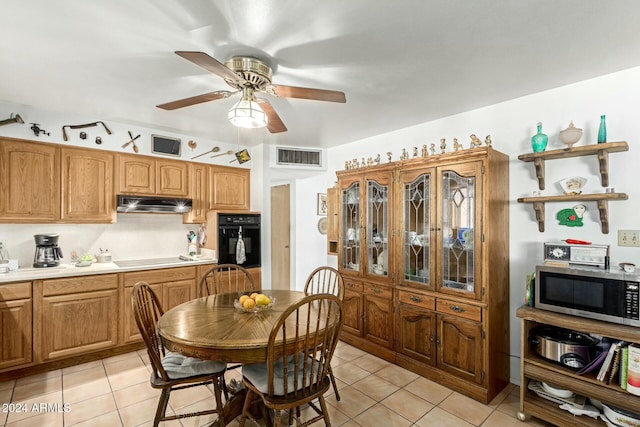 kitchen featuring ceiling fan, stovetop, oven, and light tile patterned floors