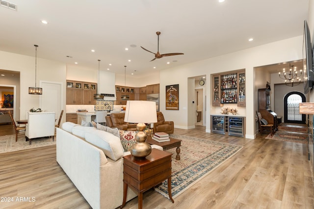 living room featuring ceiling fan, indoor bar, beverage cooler, and light hardwood / wood-style floors