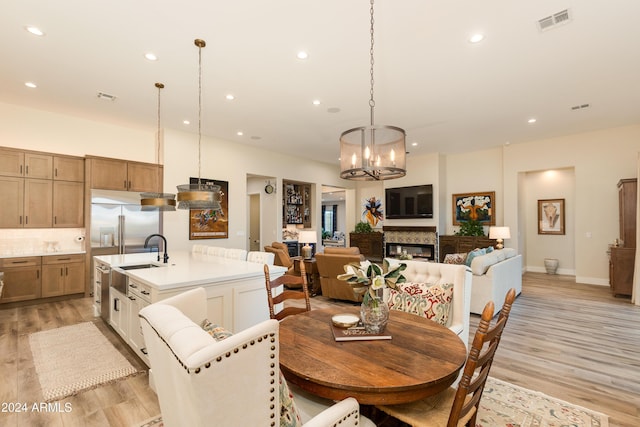 dining room with sink, light hardwood / wood-style flooring, and a notable chandelier