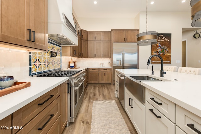 kitchen featuring premium range hood, pendant lighting, white cabinetry, backsplash, and high end appliances