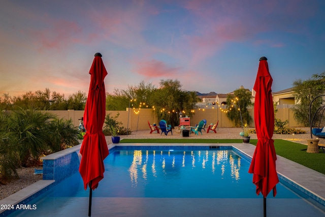 pool at dusk featuring an outdoor fire pit