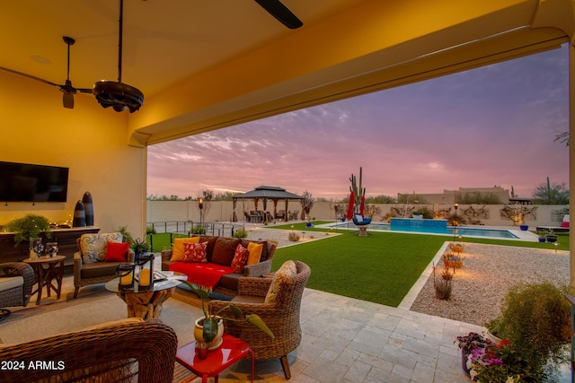 patio terrace at dusk with pool water feature, a gazebo, ceiling fan, an outdoor hangout area, and a fenced in pool