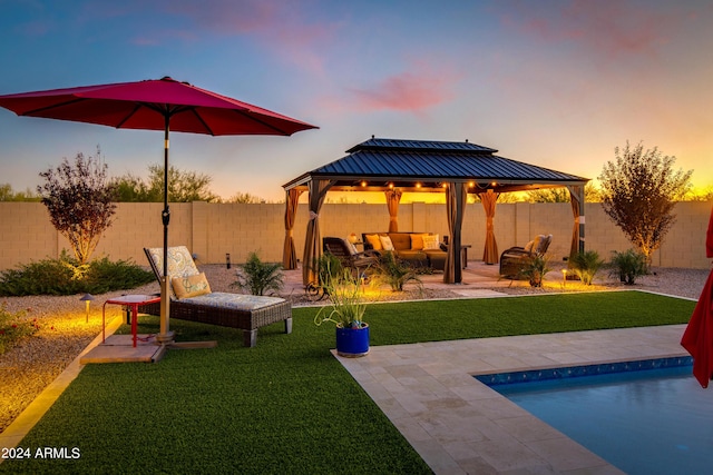 pool at dusk featuring an outdoor living space, a gazebo, a patio area, and a yard