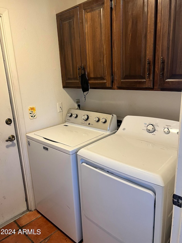 laundry room featuring dark tile patterned flooring, cabinets, and washing machine and dryer