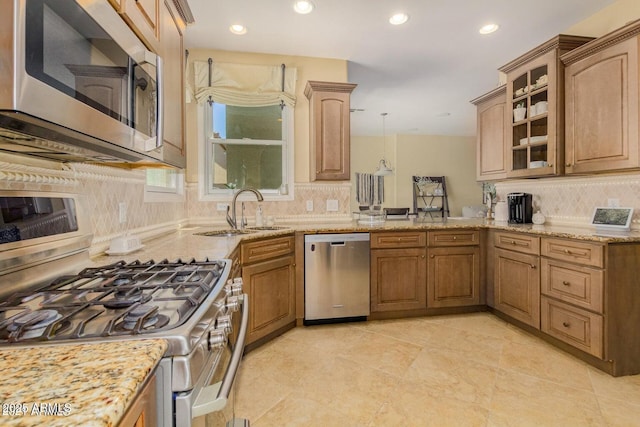 kitchen with glass insert cabinets, light stone countertops, recessed lighting, stainless steel appliances, and a sink