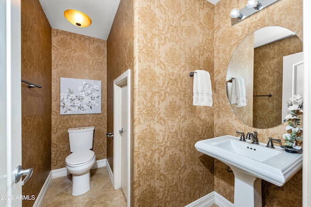 bathroom featuring tile patterned flooring, toilet, baseboards, and wallpapered walls