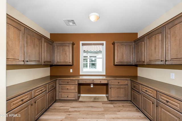 kitchen featuring dark countertops, visible vents, built in study area, and light wood-style floors