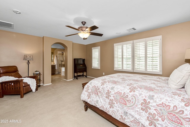 bedroom with baseboards, arched walkways, visible vents, and light carpet