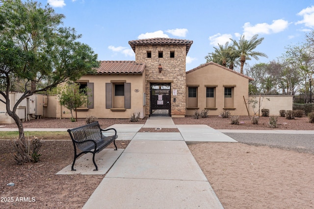 view of front of home featuring a gate, fence, stucco siding, stone siding, and a tile roof