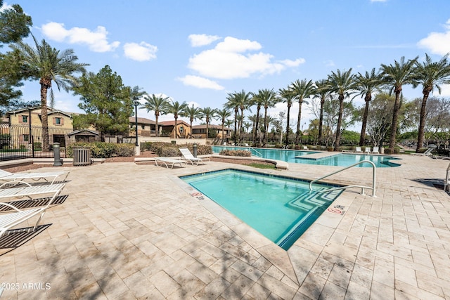 pool with a patio area and fence