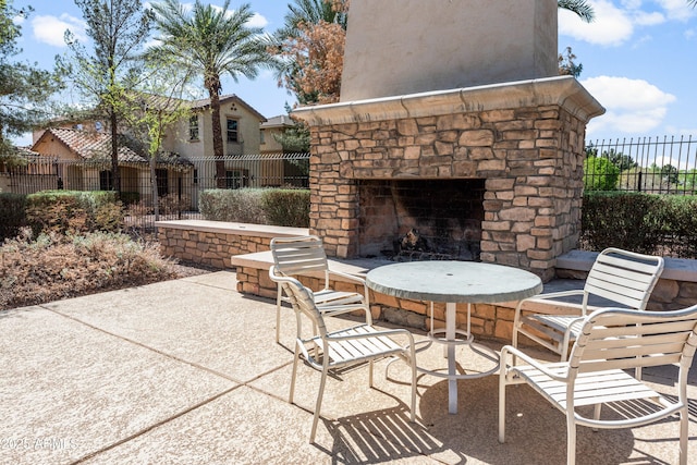 view of patio featuring fence and an outdoor stone fireplace