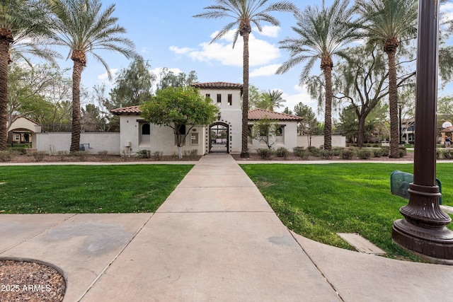 mediterranean / spanish-style home featuring a front yard, a tile roof, and stucco siding