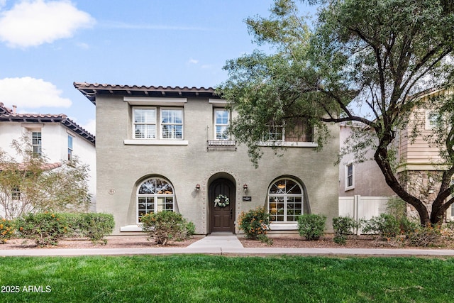 mediterranean / spanish home featuring a front lawn and stucco siding