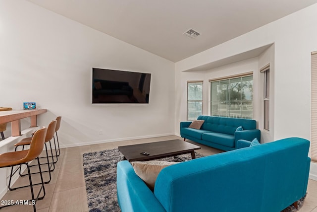 tiled living area with visible vents, vaulted ceiling, and baseboards