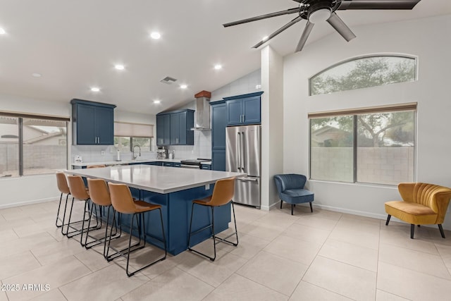 kitchen with stainless steel appliances, light countertops, a kitchen island, a sink, and blue cabinets