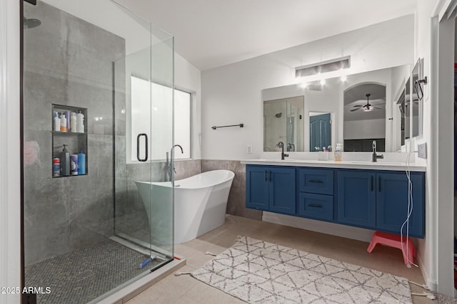 full bath with double vanity, tile patterned floors, a freestanding bath, a shower stall, and a sink