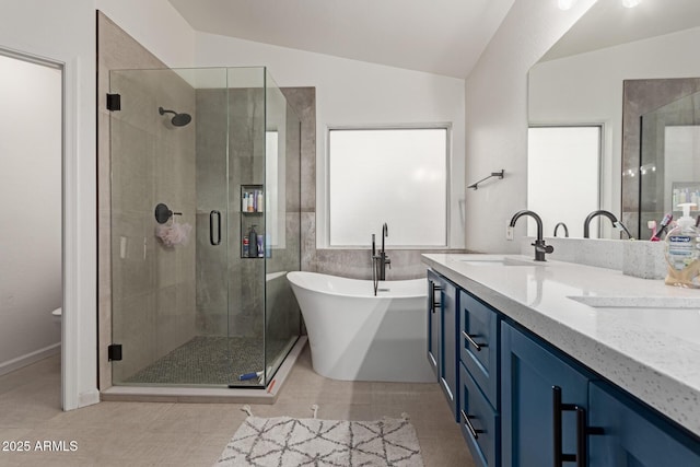 bathroom with a stall shower, tile patterned flooring, a freestanding tub, and a sink