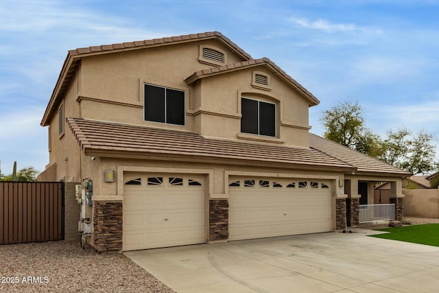 traditional-style house featuring driveway, a garage, a tiled roof, fence, and stucco siding