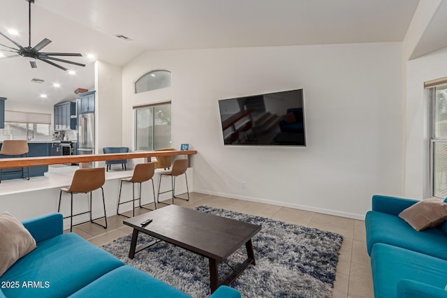 living room with light tile patterned floors, visible vents, a healthy amount of sunlight, vaulted ceiling, and baseboards