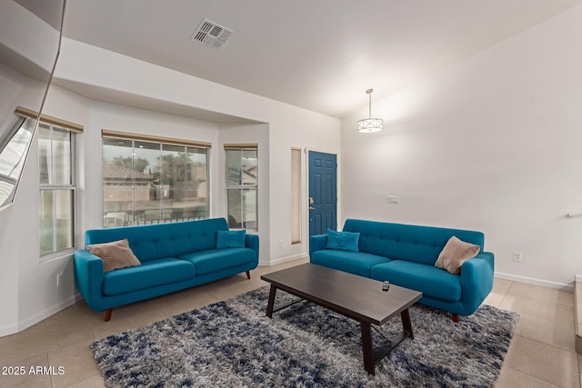 tiled living room featuring visible vents, vaulted ceiling, and baseboards