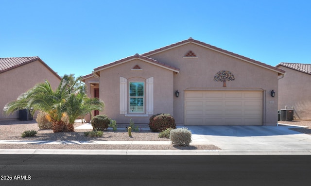 mediterranean / spanish house featuring a tile roof, stucco siding, an attached garage, central AC, and driveway