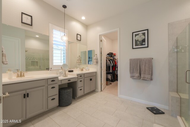 bathroom featuring a spacious closet, a shower stall, vanity, baseboards, and tile patterned floors