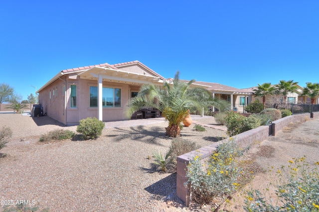 view of front of home with a tile roof, fence, and stucco siding