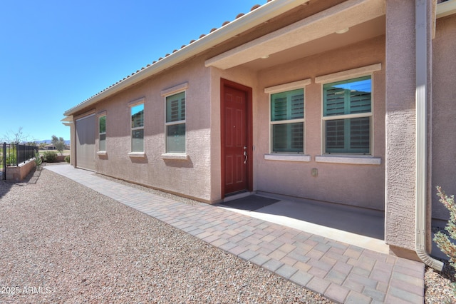 property entrance with a patio area, fence, and stucco siding