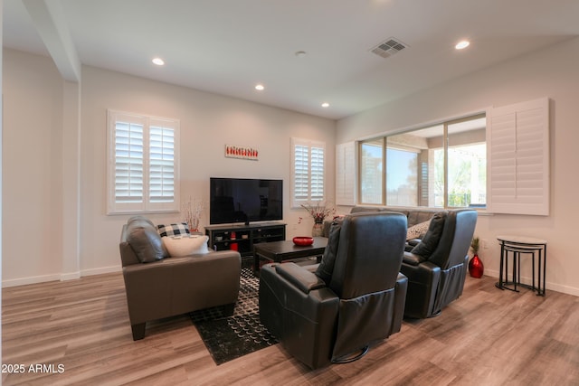 living area with light wood-type flooring, a healthy amount of sunlight, visible vents, and recessed lighting